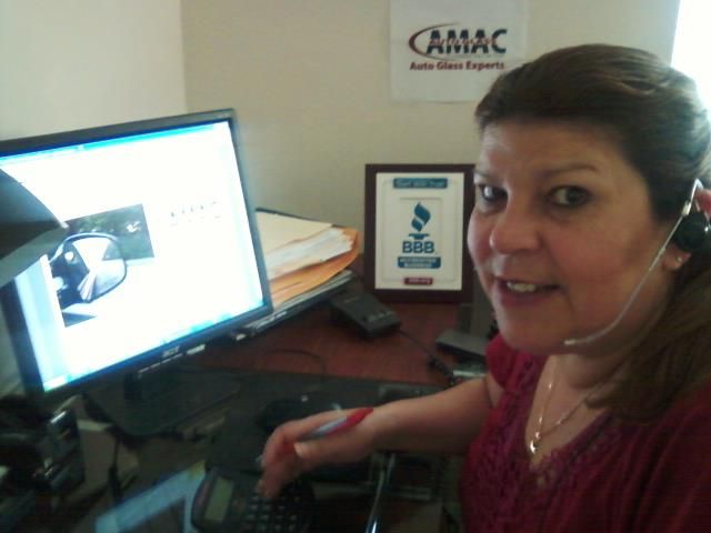 A woman wearing a headset is sitting at a desk in front of a camac sign