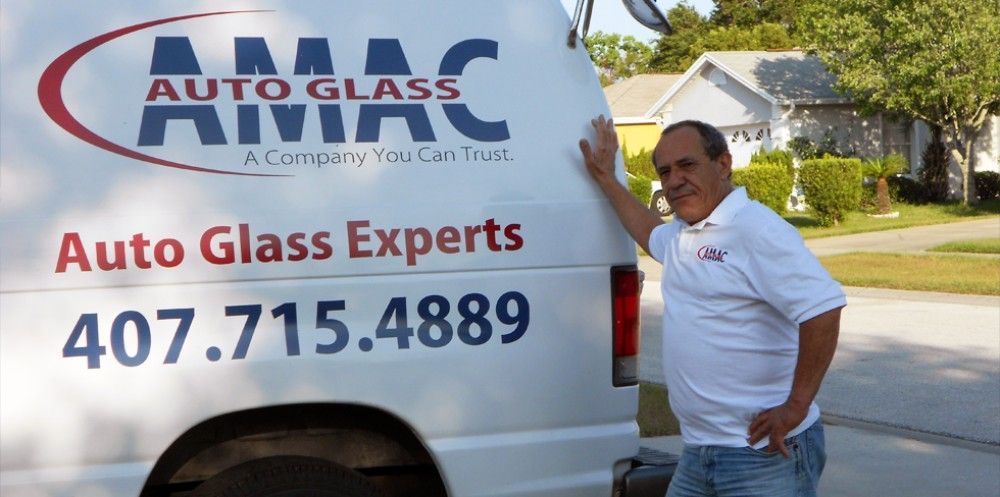 A man standing next to a white van that says auto glass experts