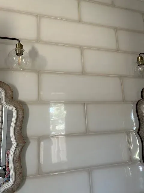 White subway tile wall with decorative mirrors and two light fixtures.