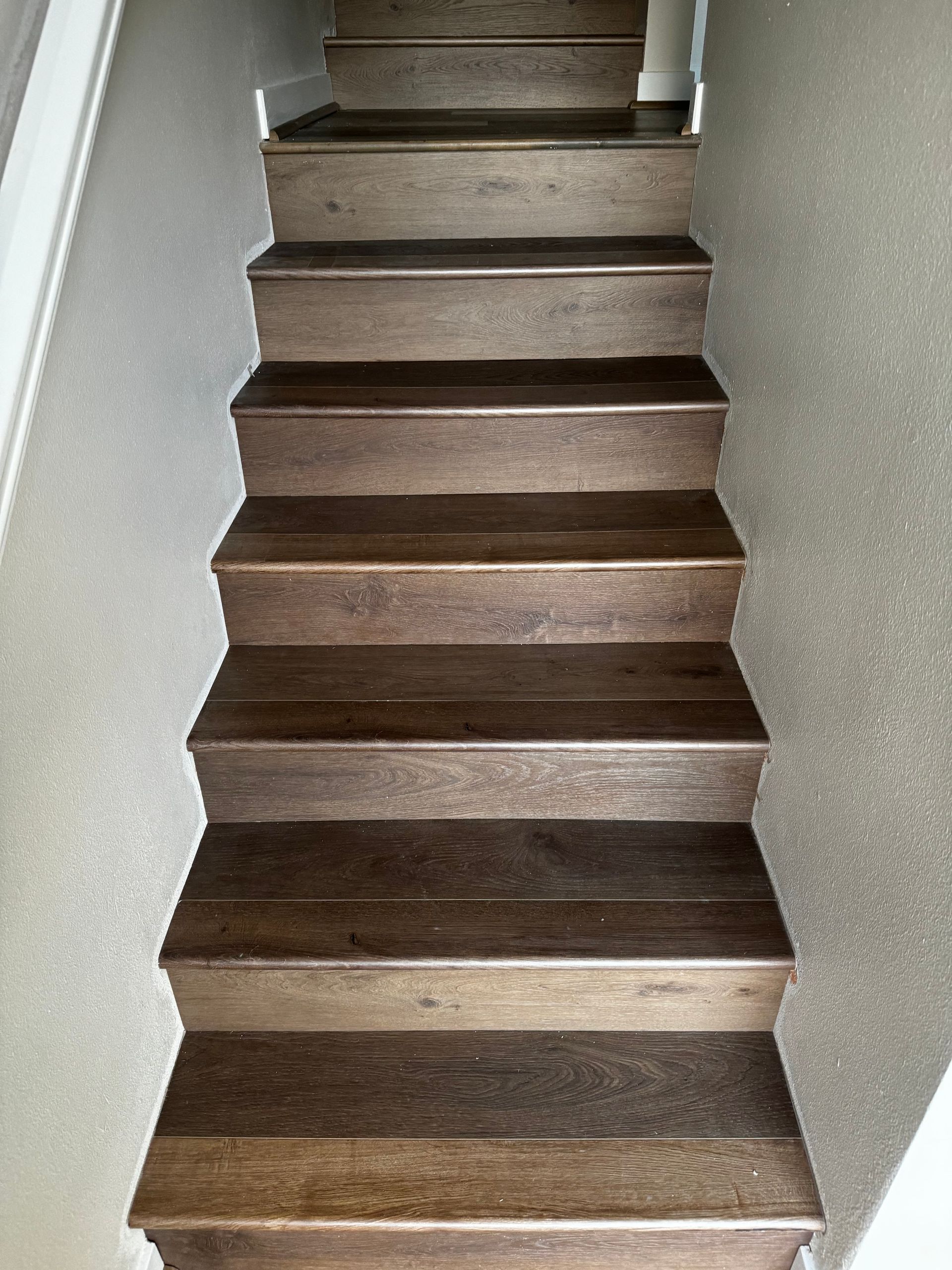 Wooden stairs viewed from above, descending between beige walls.