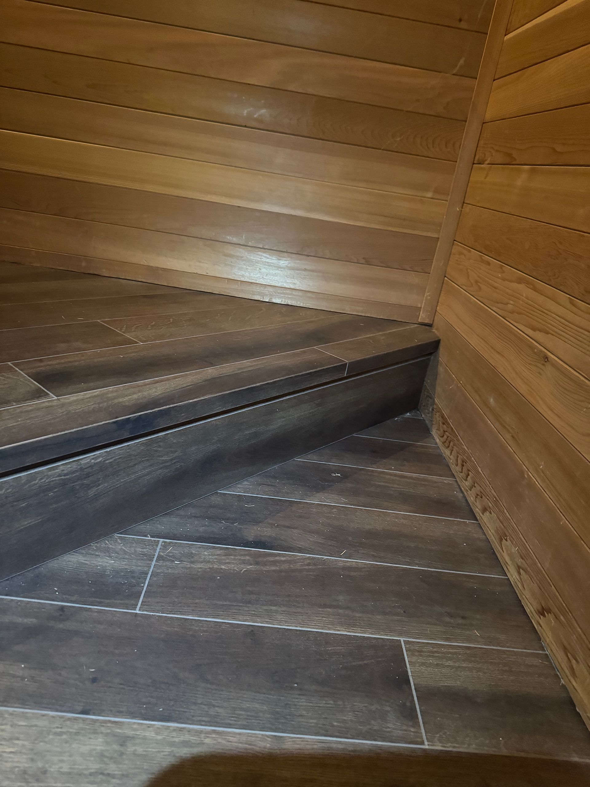 Wooden sauna interior with horizontal wood paneling and bench.