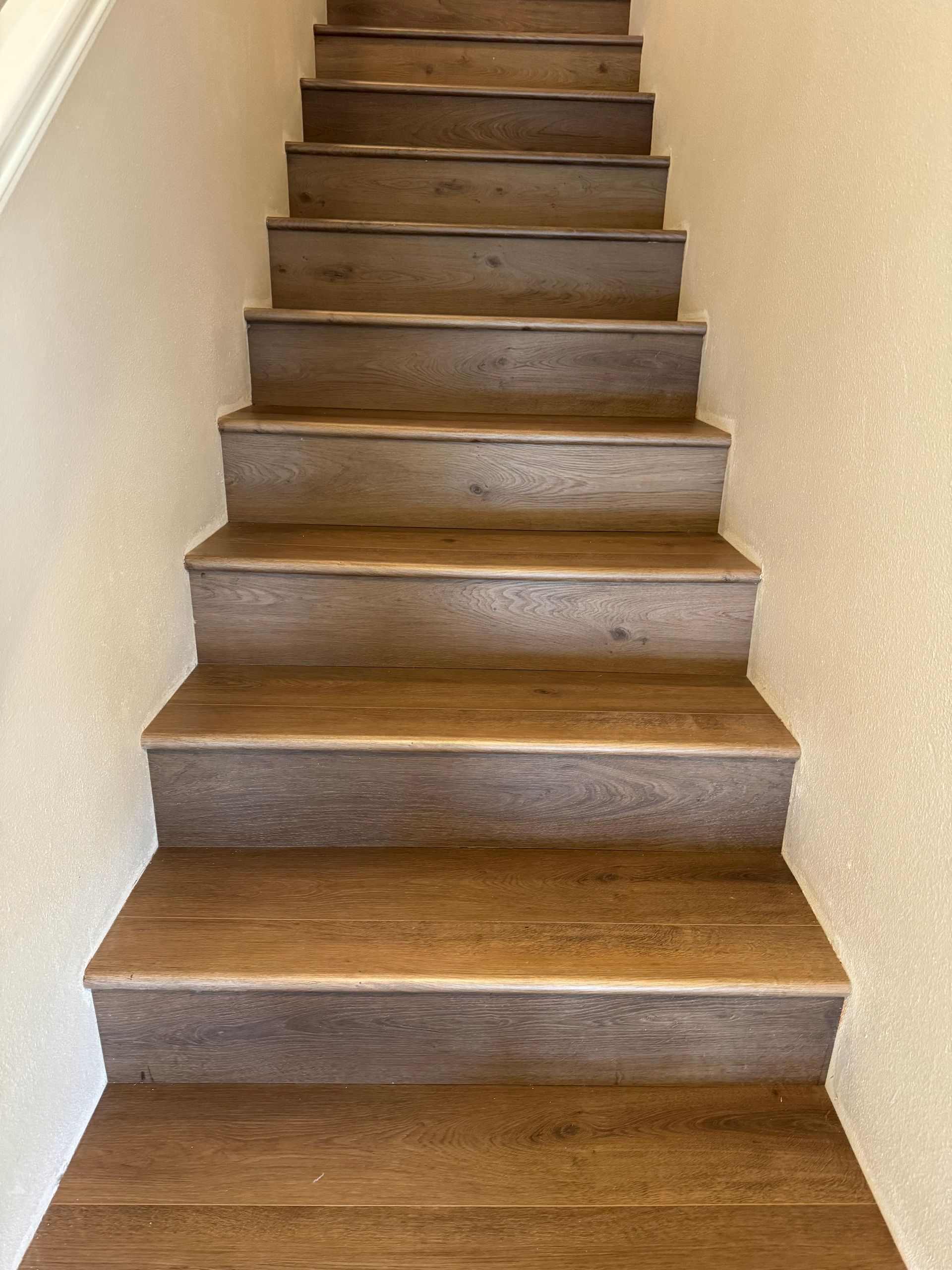 Wooden staircase ascending with steps. Beige walls on either side.