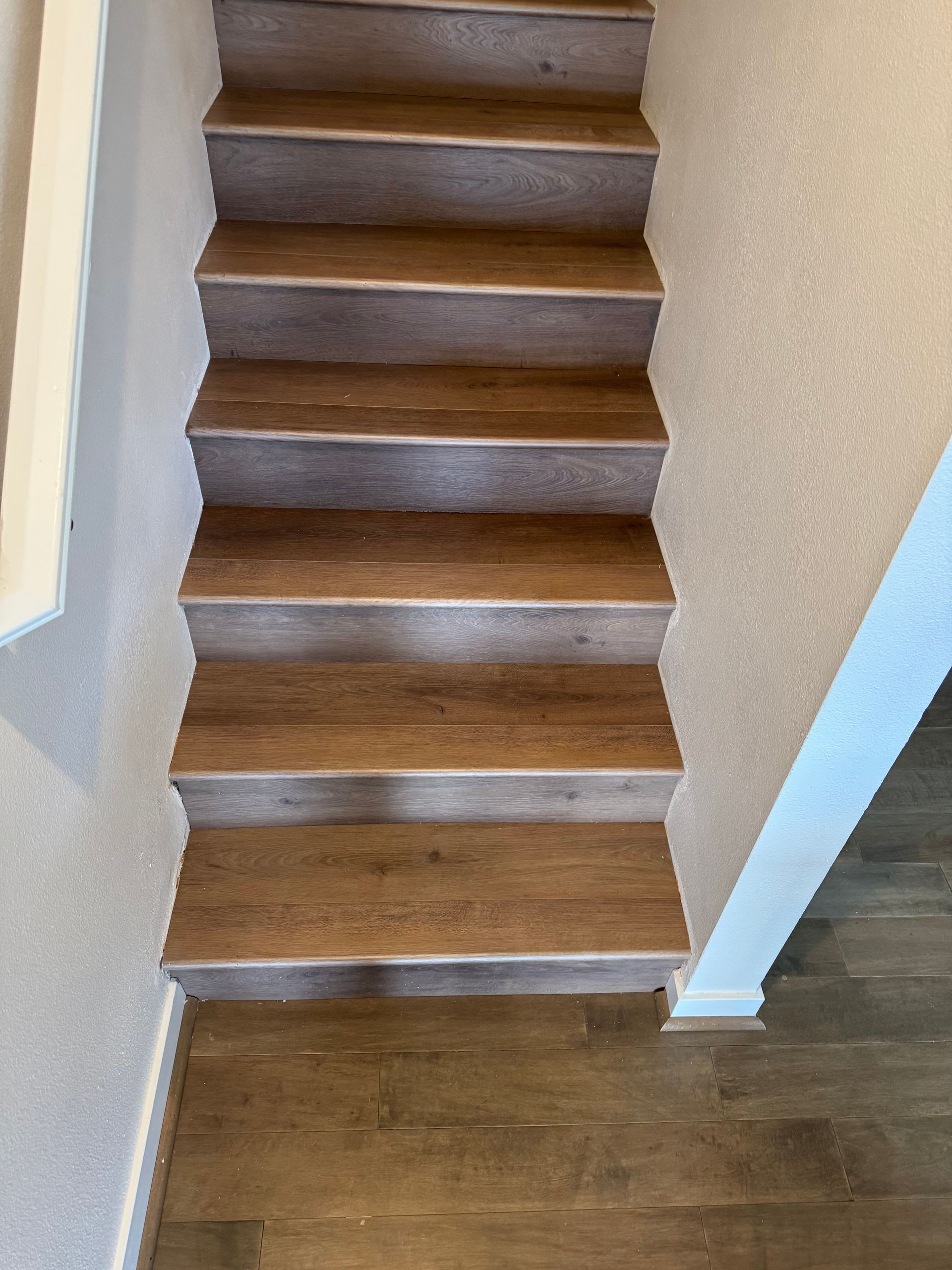 Staircase with wooden steps and a light-colored carpeted landing at the top and bottom.