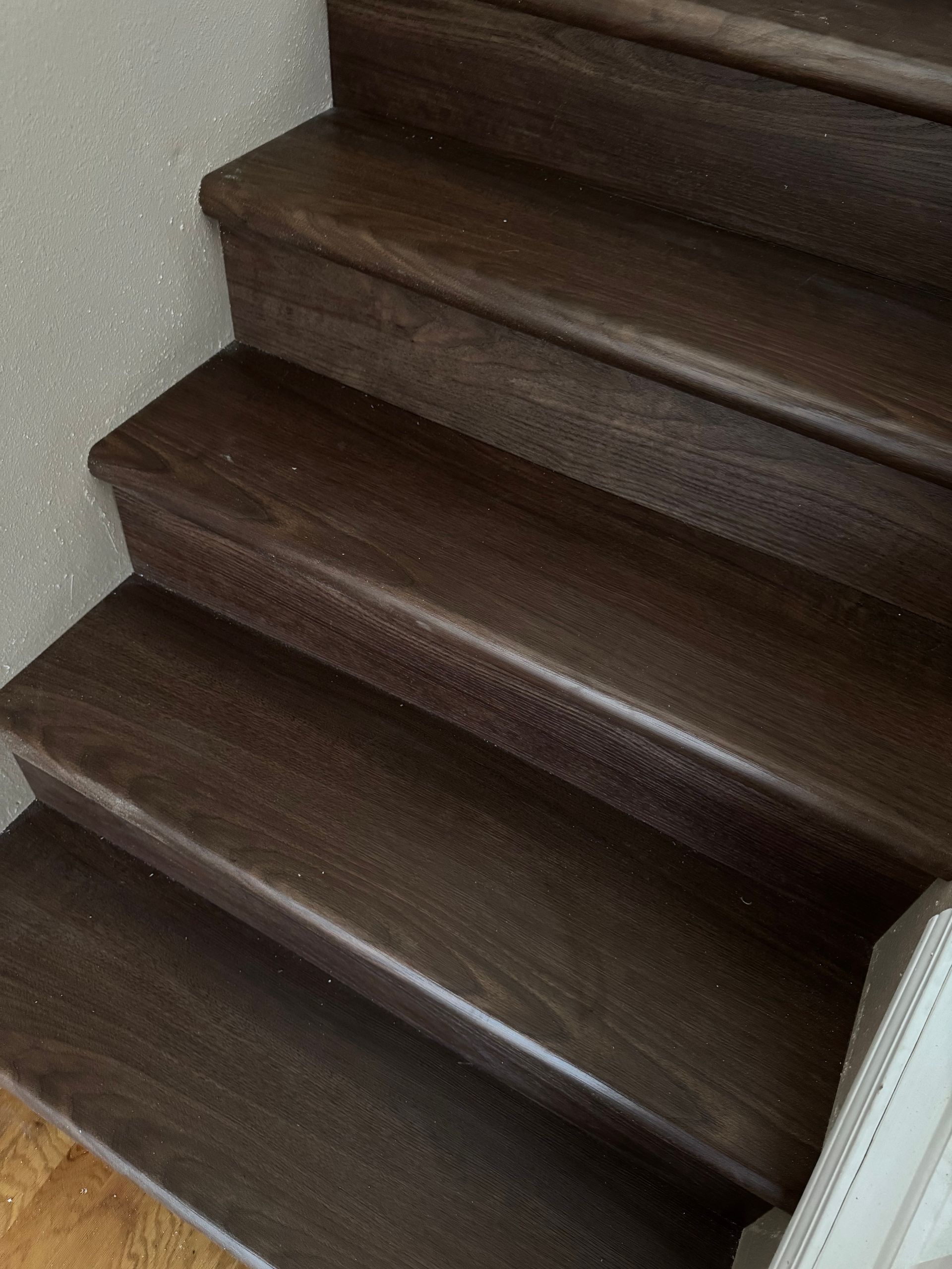 Dark wood staircase. Three steps visible, with smooth, brown treads and rounded edges.