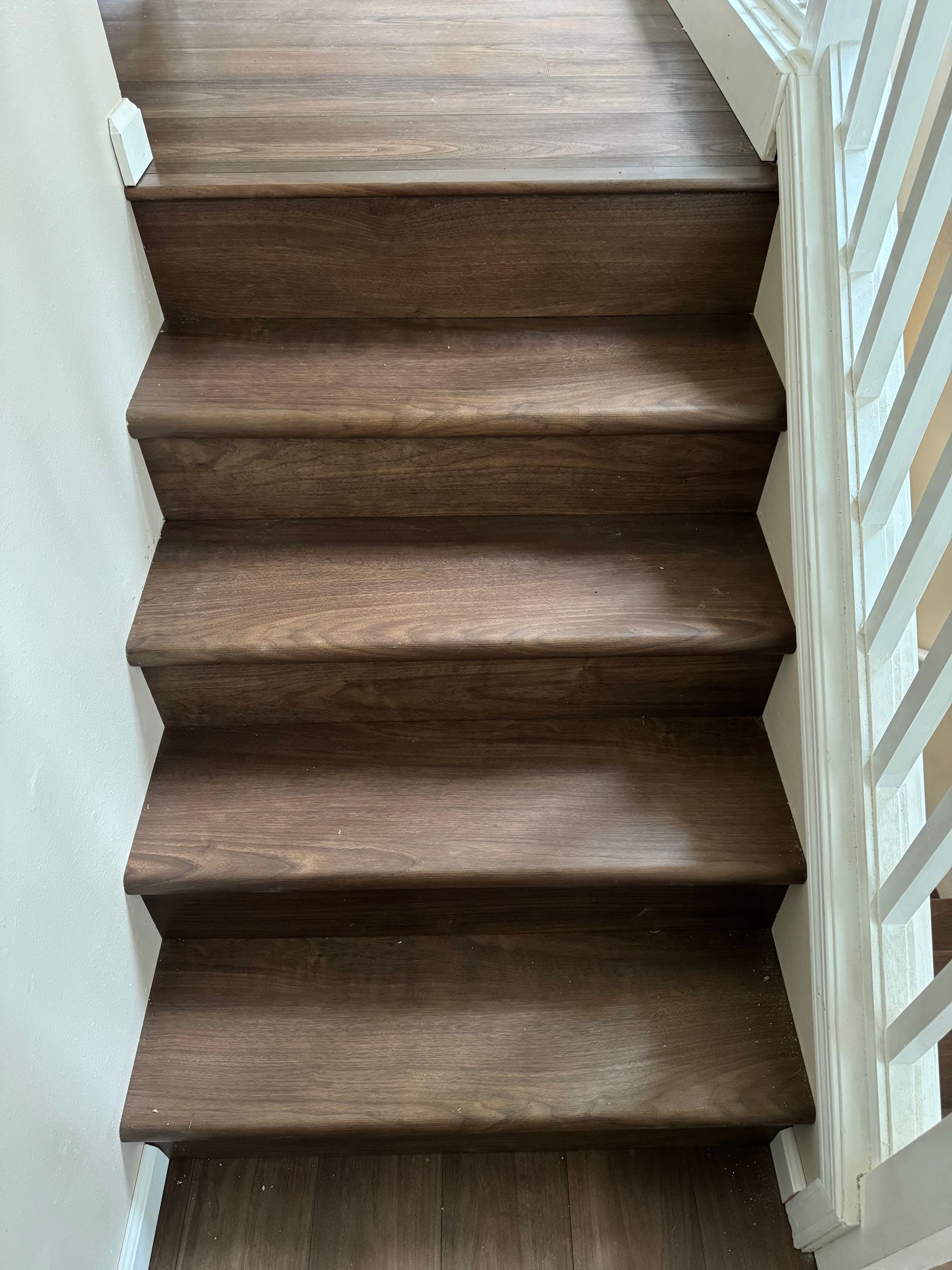 Wooden staircase with white banister, view from above.