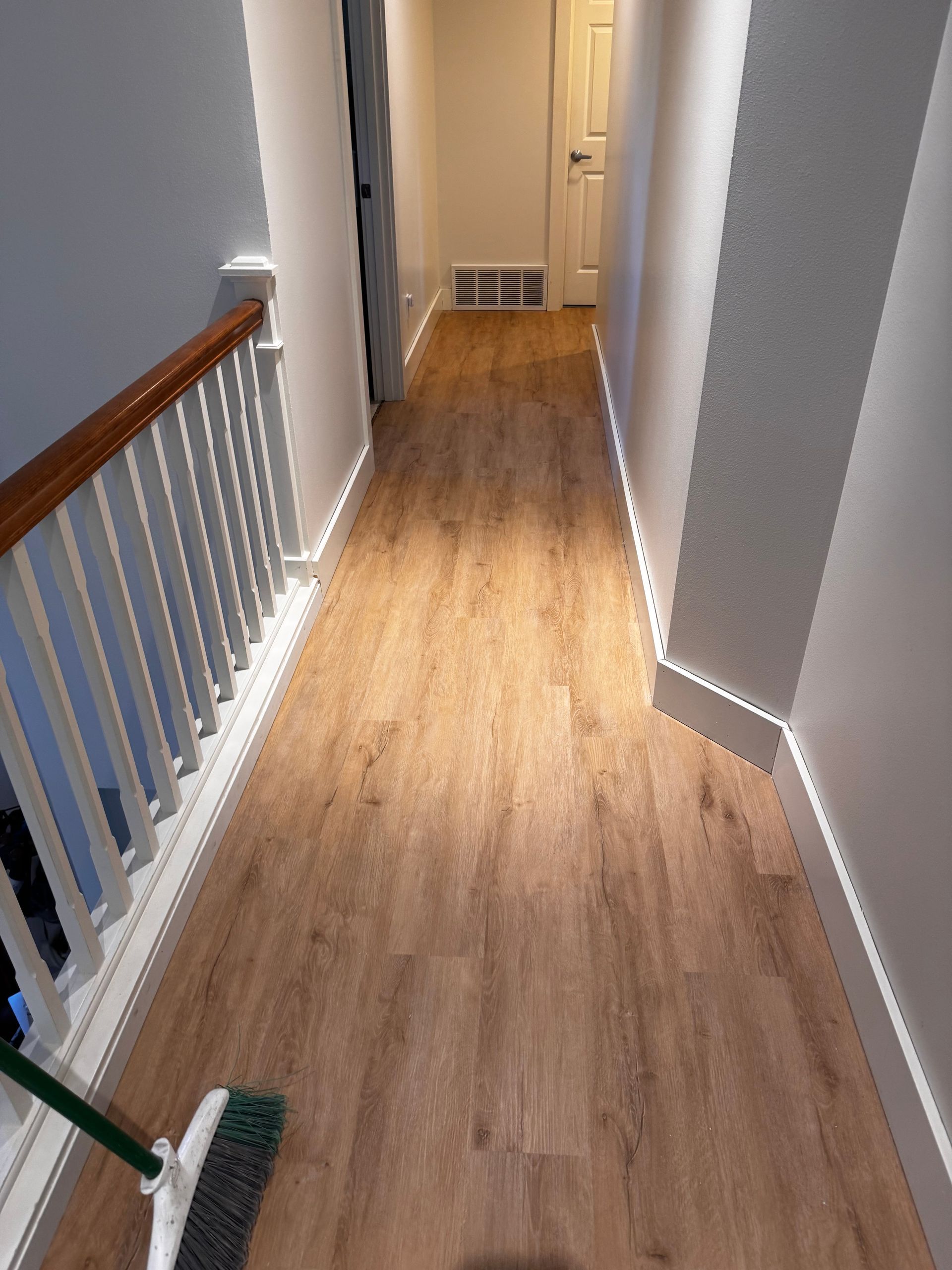Hallway with wooden floor, white walls and trim, and a railing on the left.