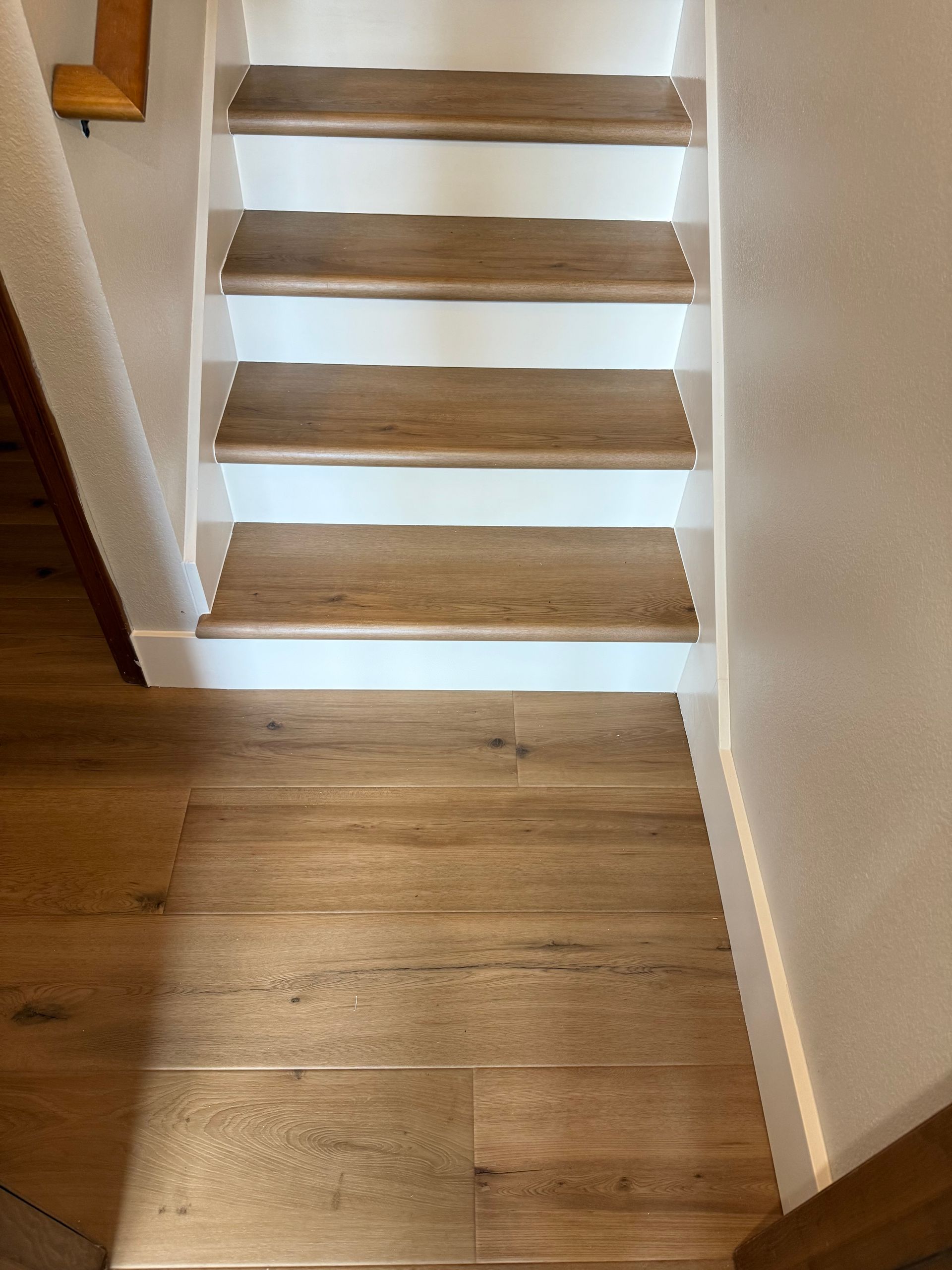 Wooden staircase with white risers. Brown flooring at bottom.