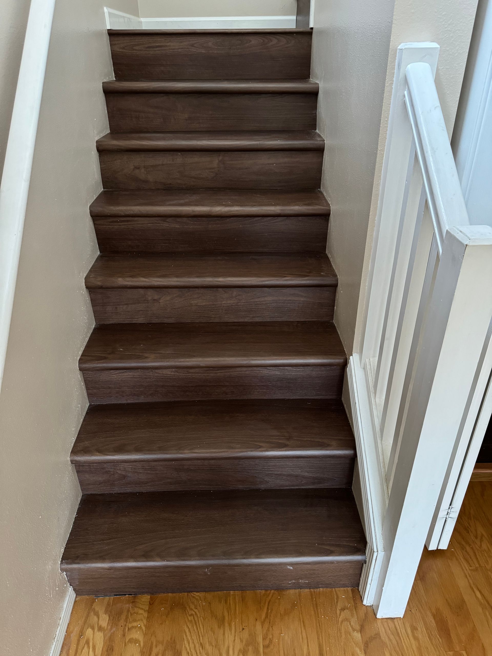 Wooden staircase with white banister, steps lead upwards.