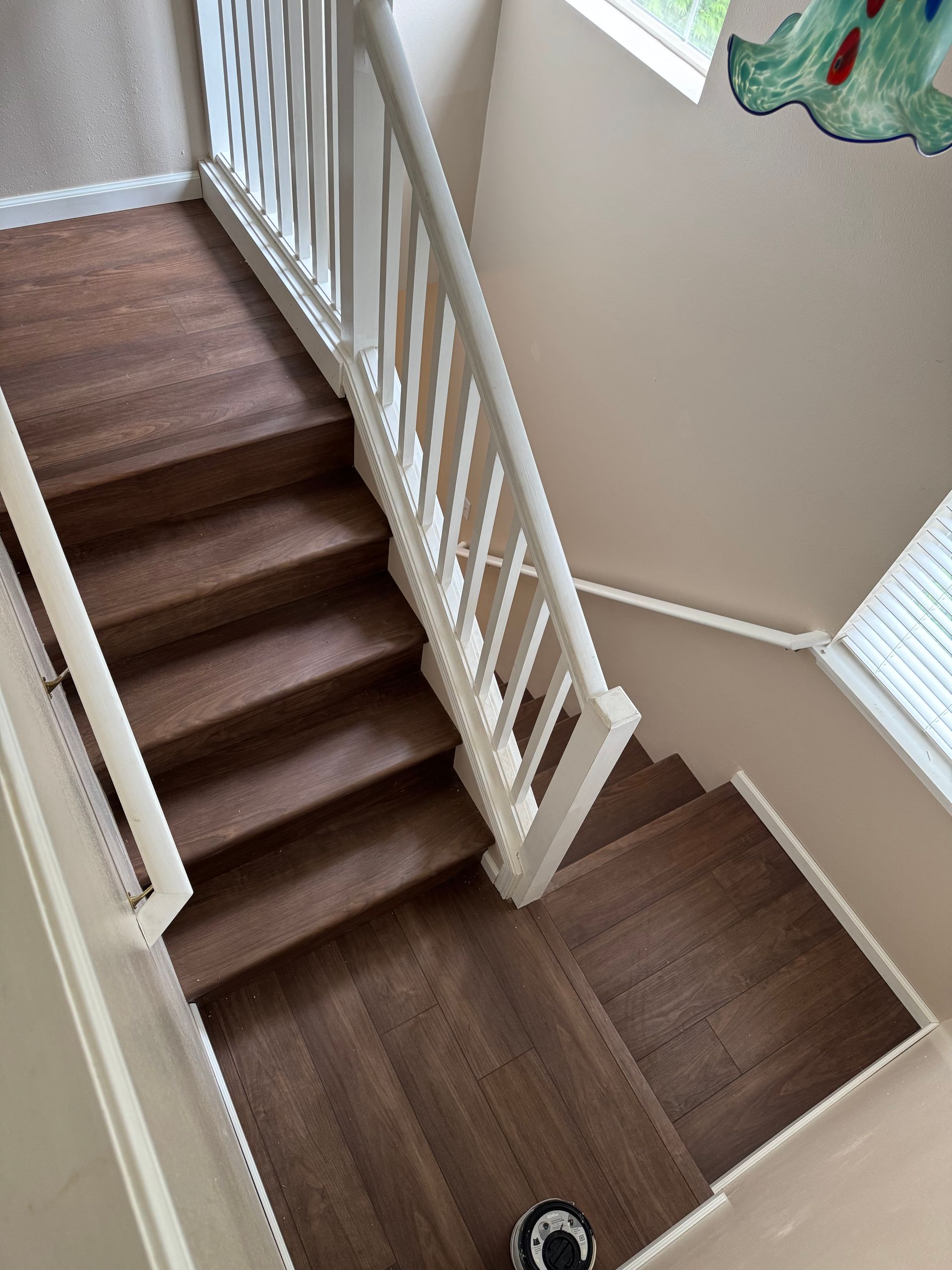Wooden staircase with white banister, viewed from above.