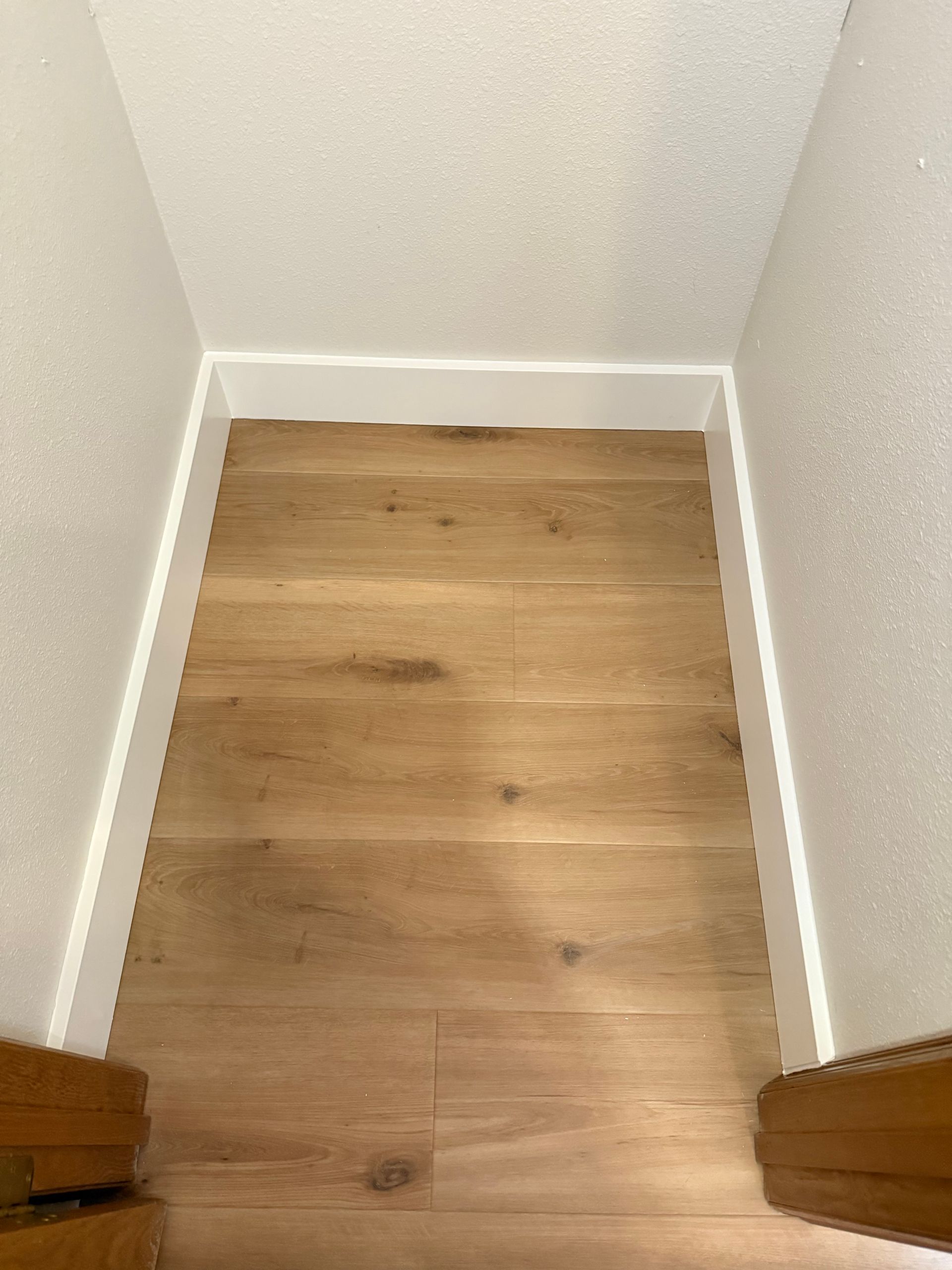 Narrow hallway with wood flooring, white trim, and walls.