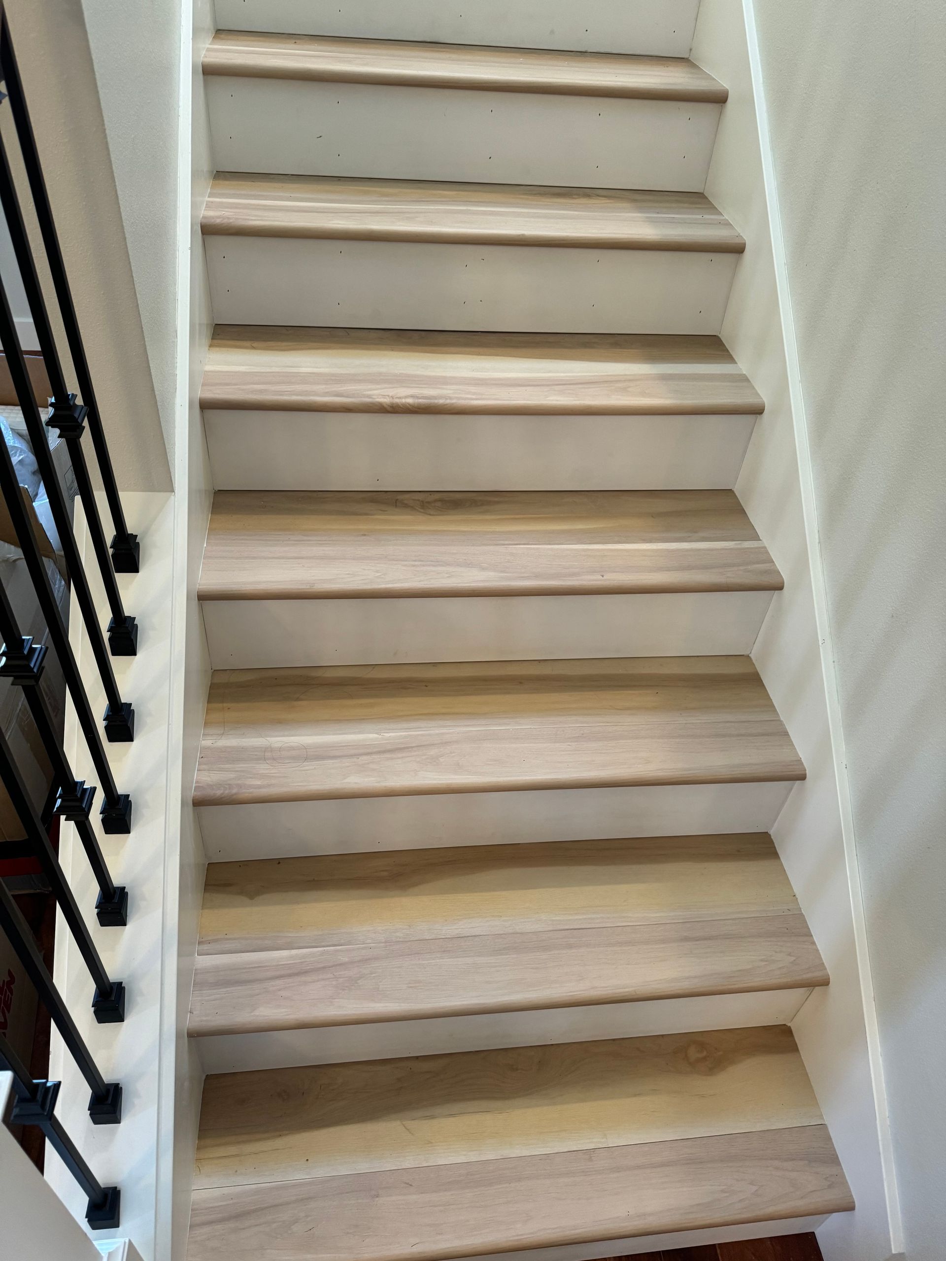 Wooden stairs with white risers and a black metal railing.