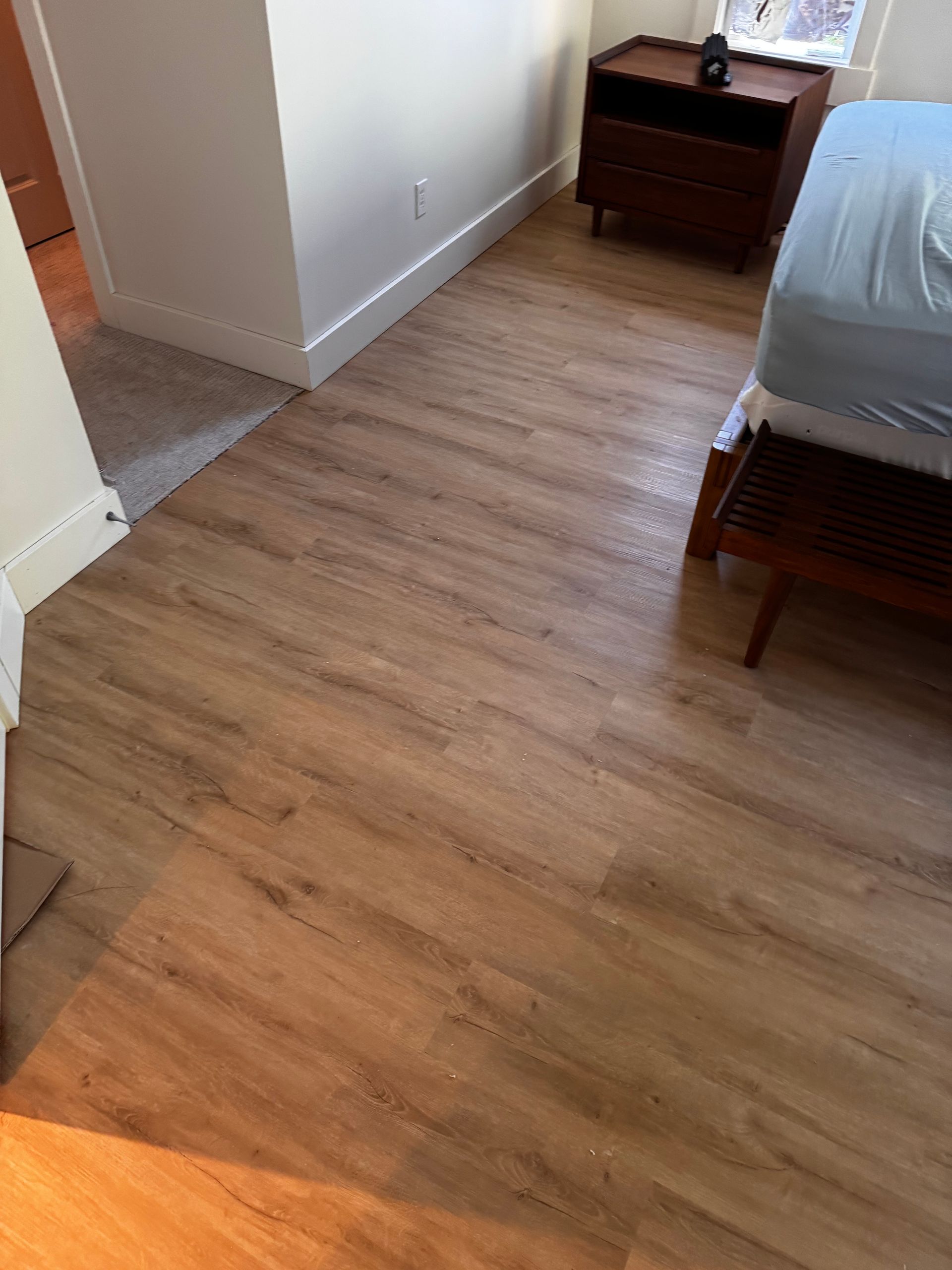 Bedroom with wood-look flooring and a bed, nightstand, and doorway.