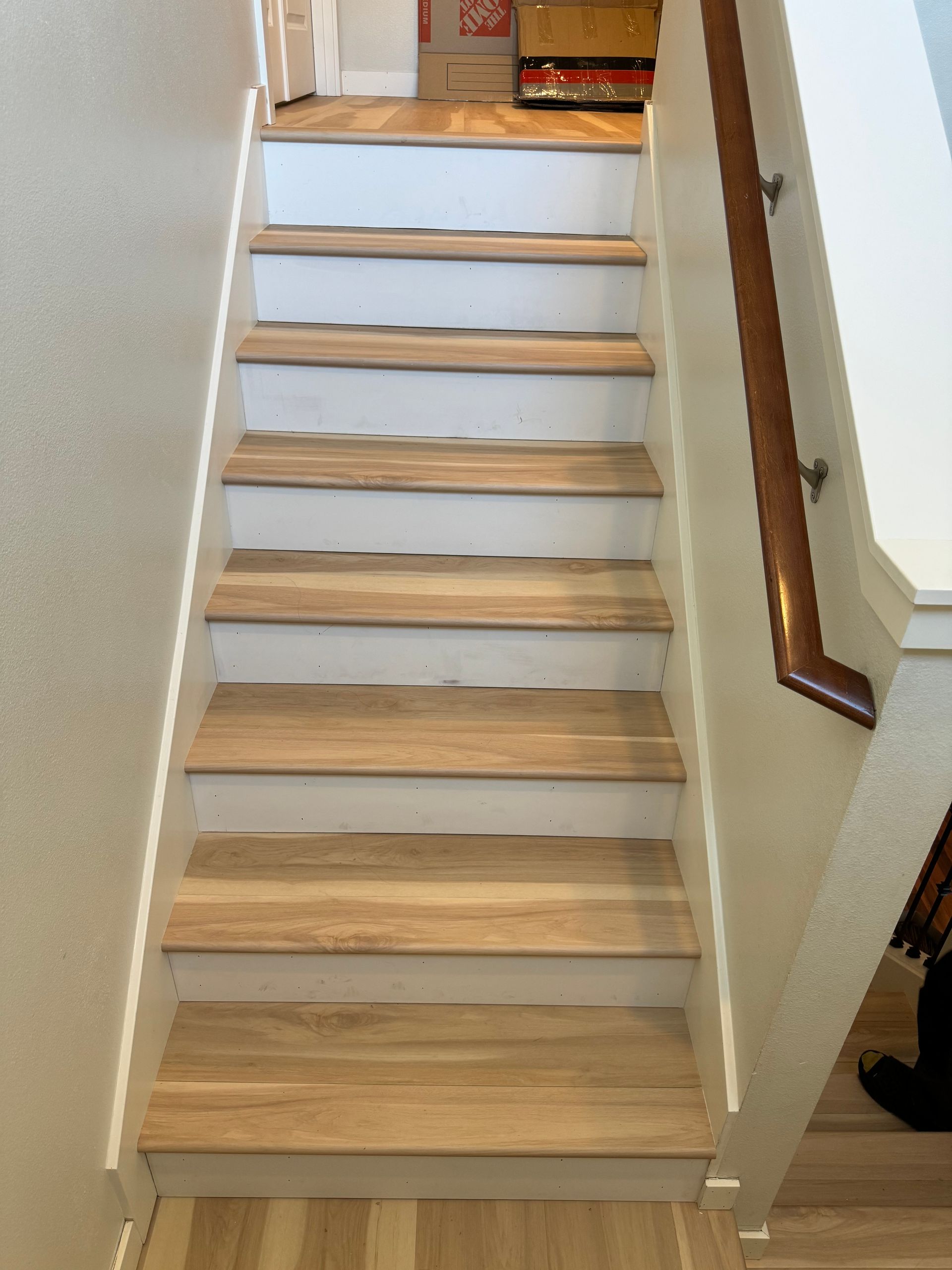 Staircase with light wood treads and white risers, leading upwards towards a landing. Handrail on the right.
