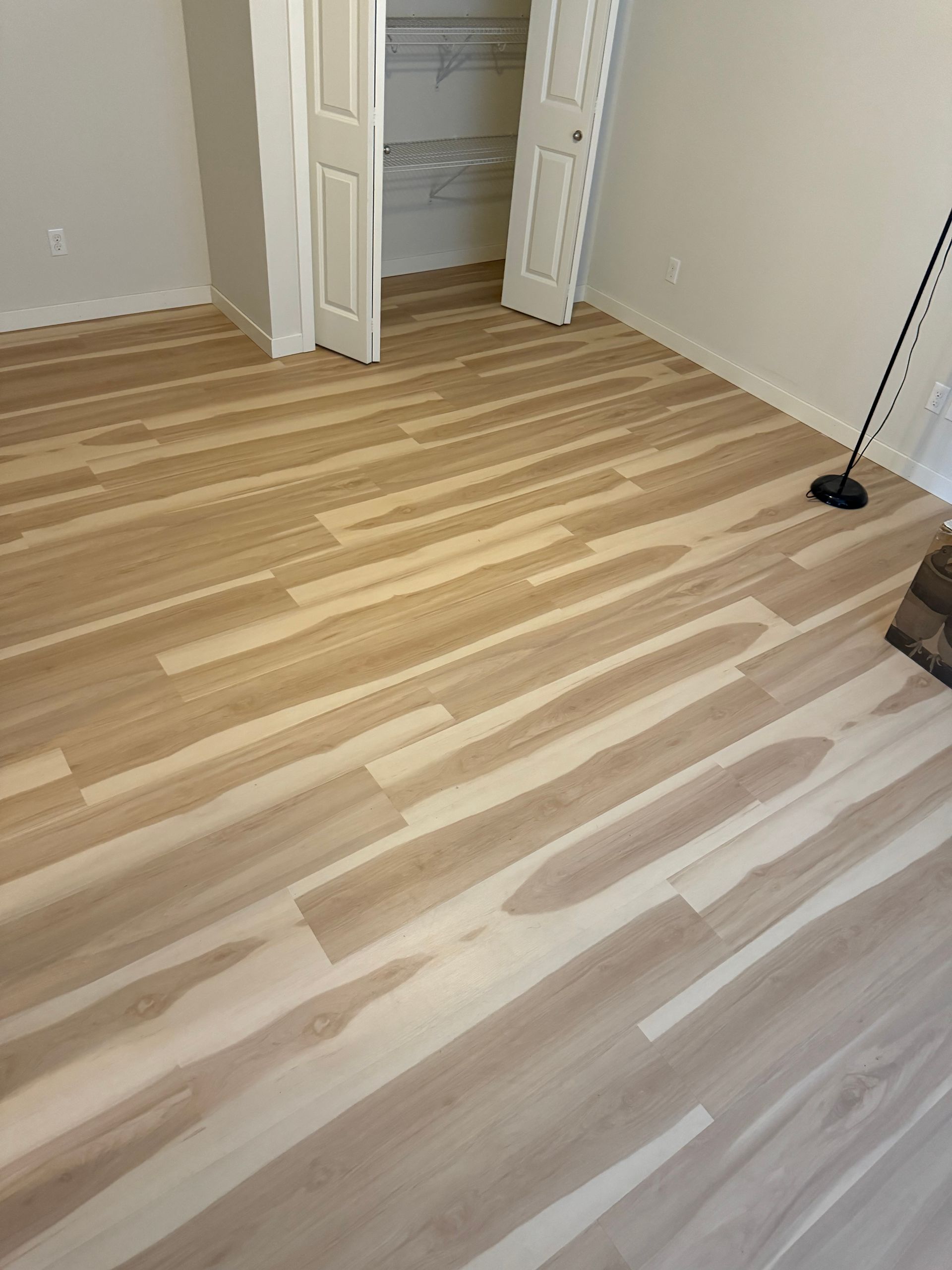 Light wood-look flooring installed in a room, with a partially open closet visible in the background.