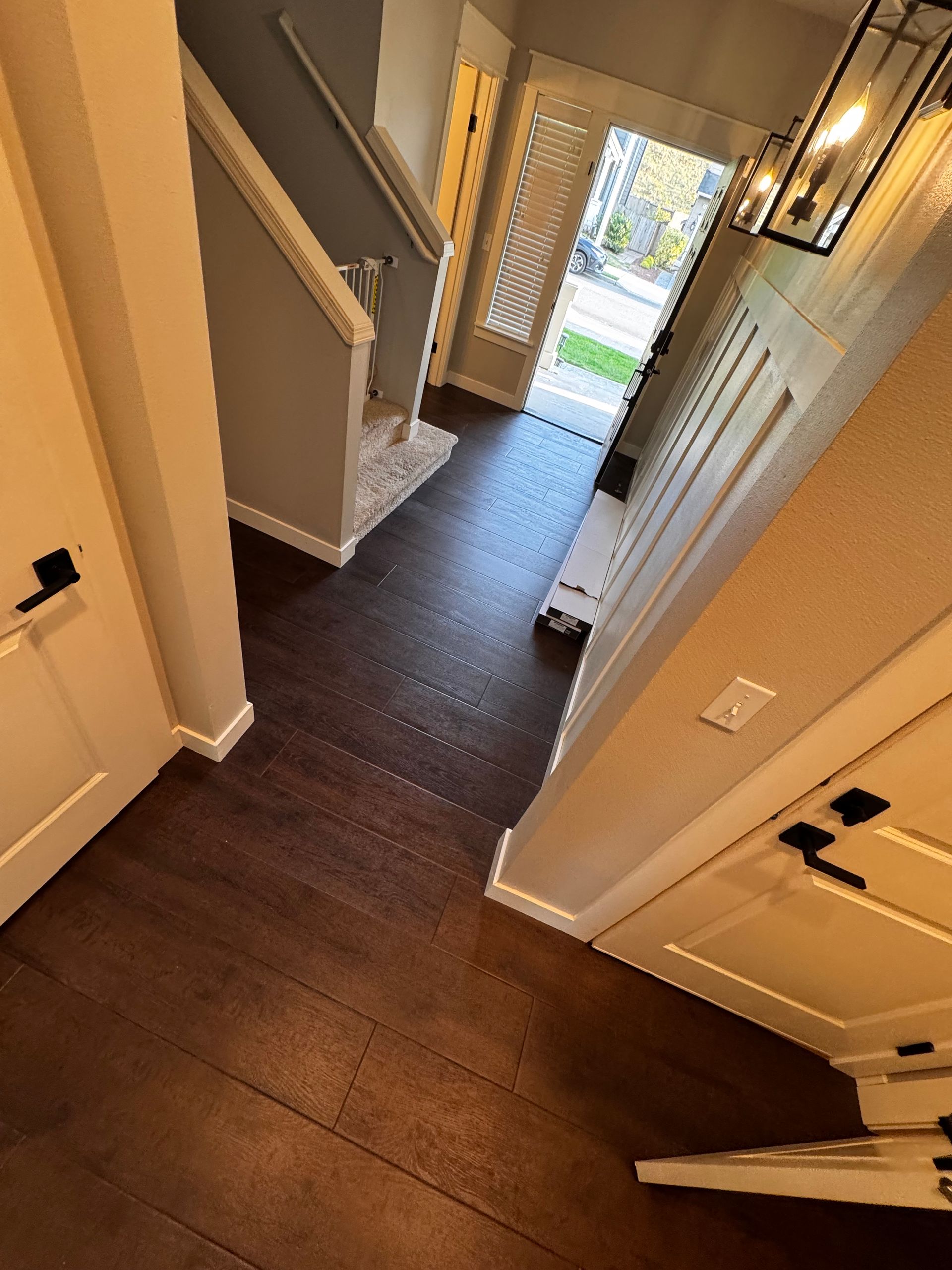 Entryway with dark wood floor, white doors, stairs, and a decorative front door.