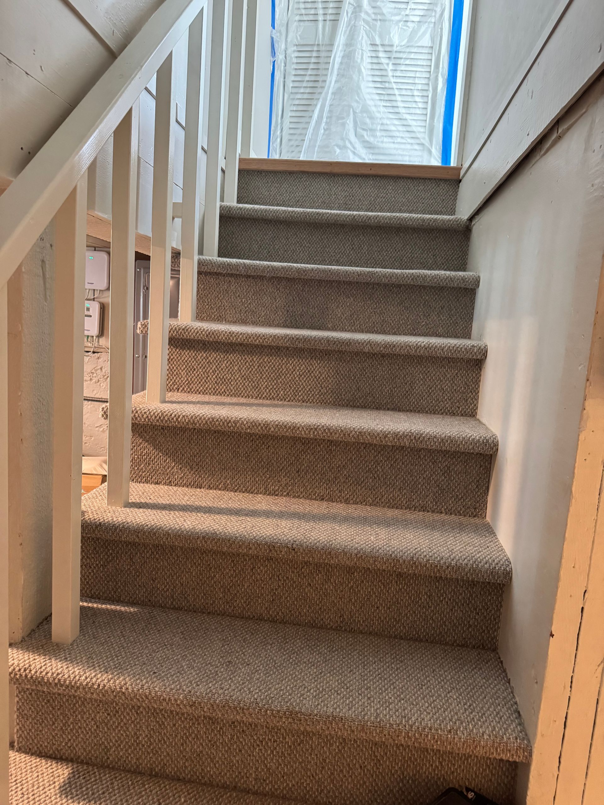 Carpeted staircase with white railing, leading upward.