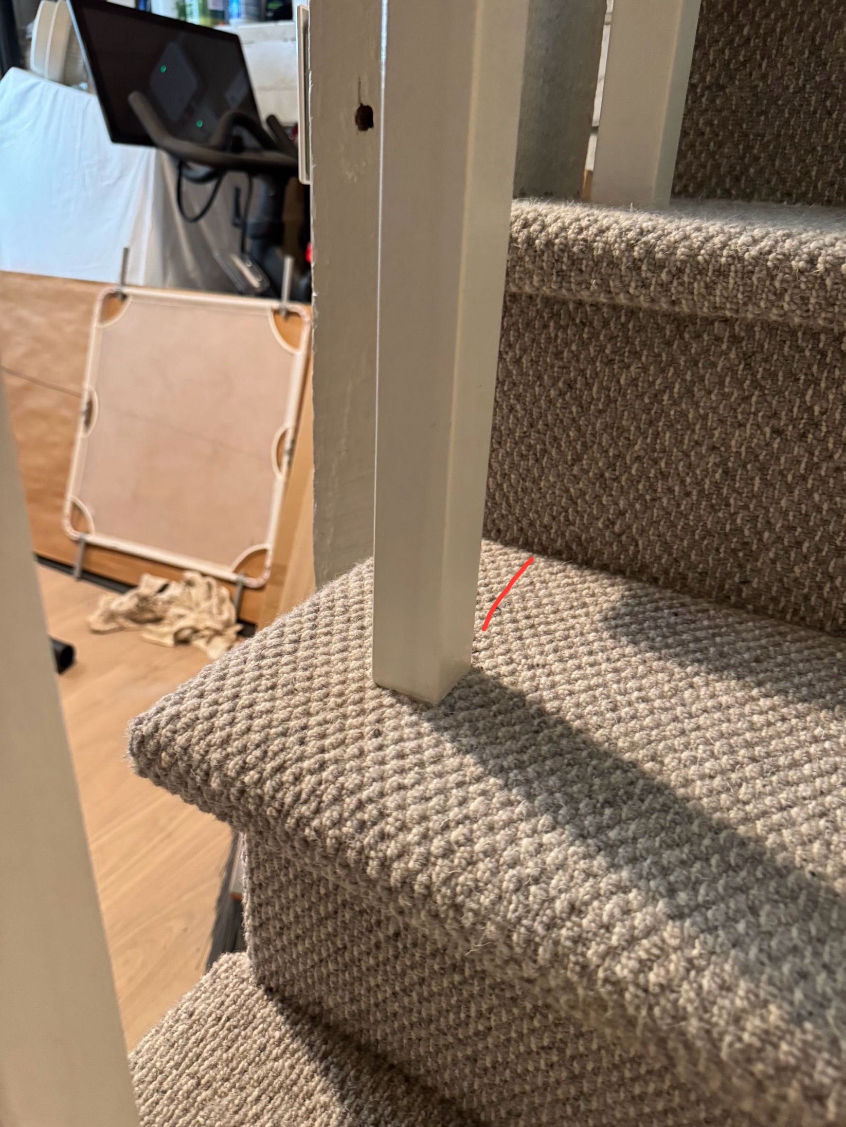Staircase with gray carpet and white railing post. Red line marks carpet.