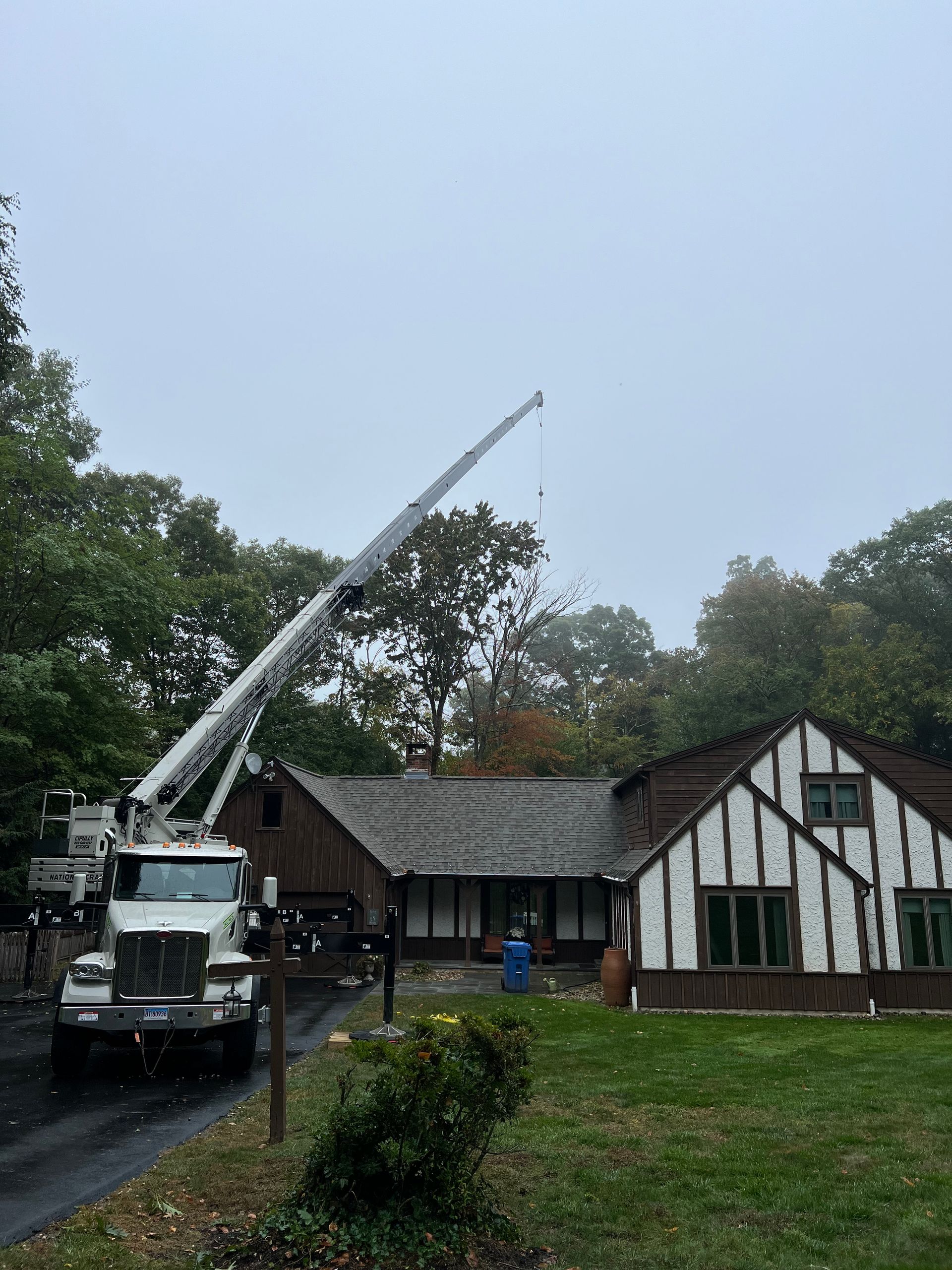 A truck with a crane on top of it is parked in front of a house.