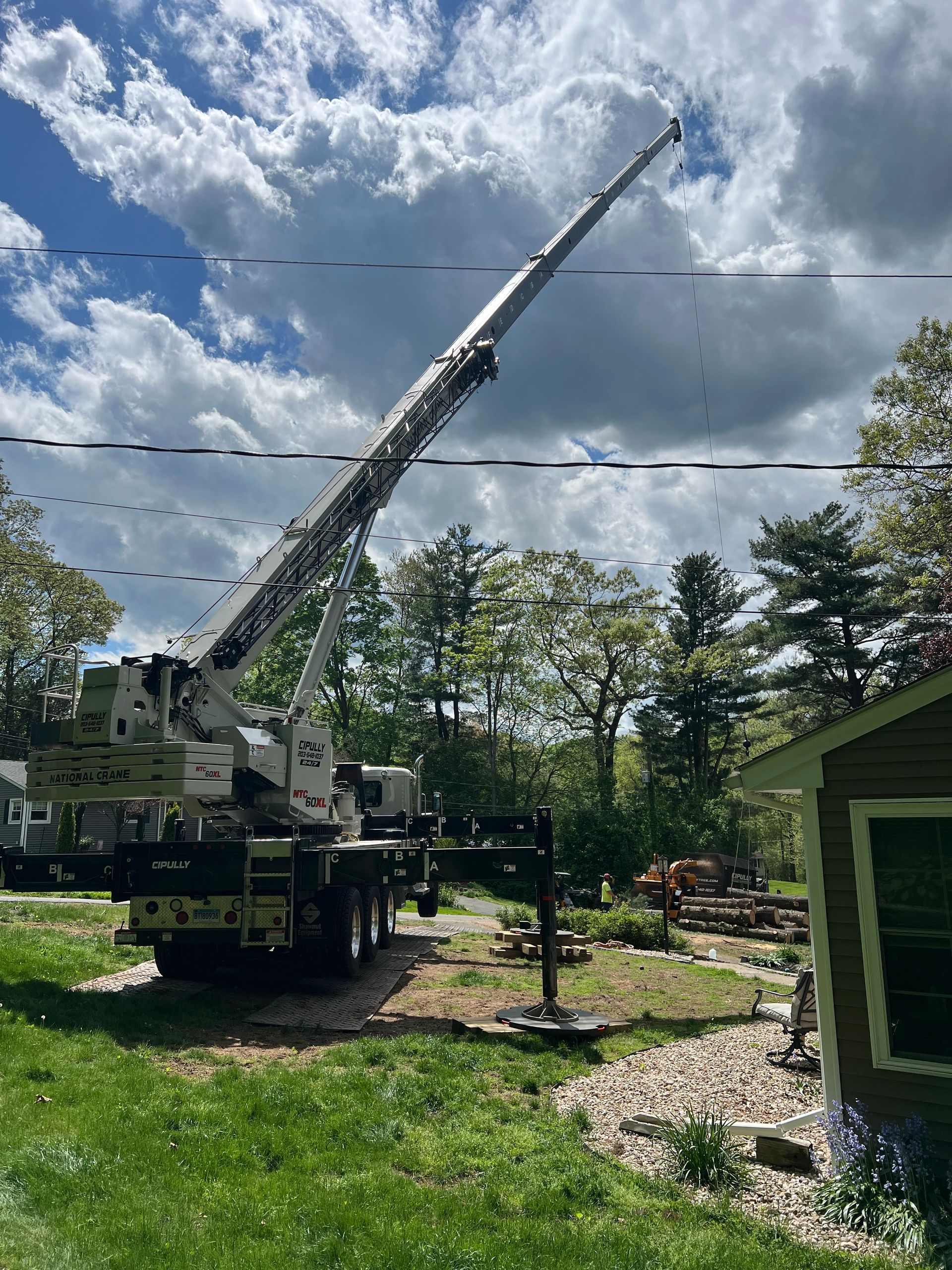 A large crane is sitting in the grass in front of a house.