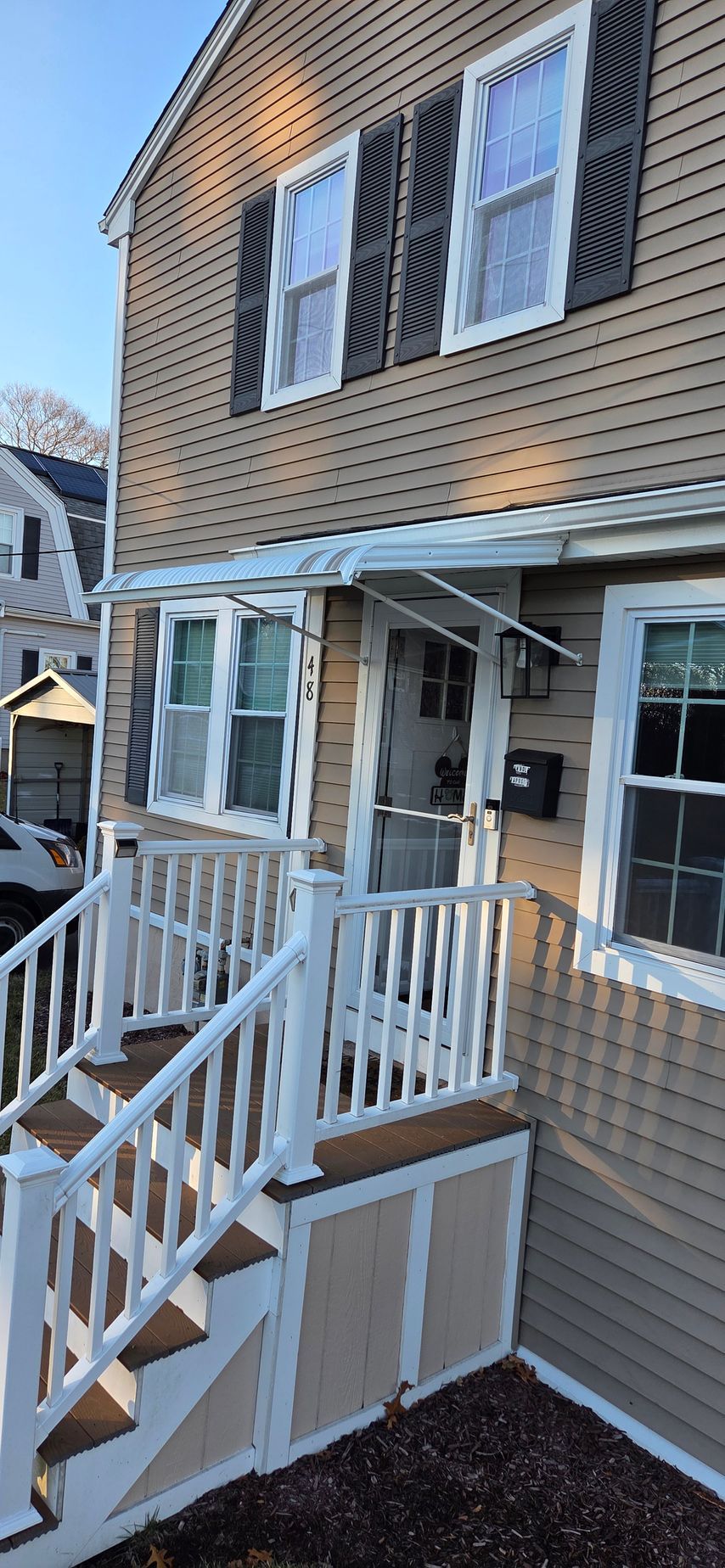 A two-story house with a porch. Steps lead to a screen door. Shutters flank the windows.