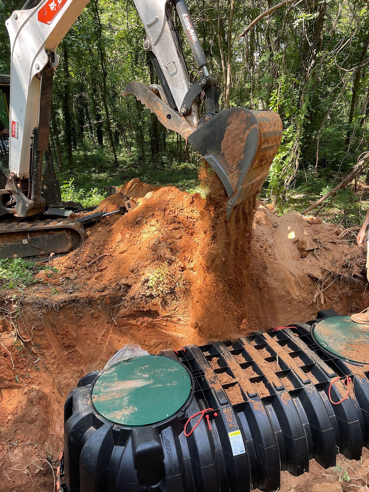 A bulldozer is digging a hole in the ground to install a septic tank.