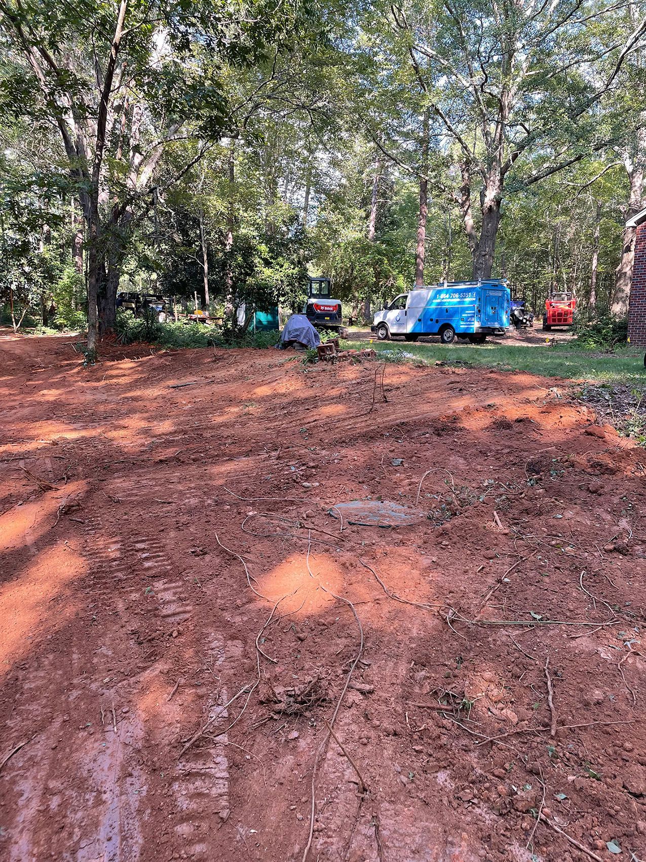 A muddy field with trees and a blue van in the background.
