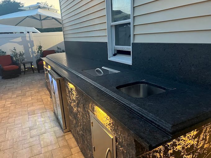 A kitchen with a sink and a window in front of a house.