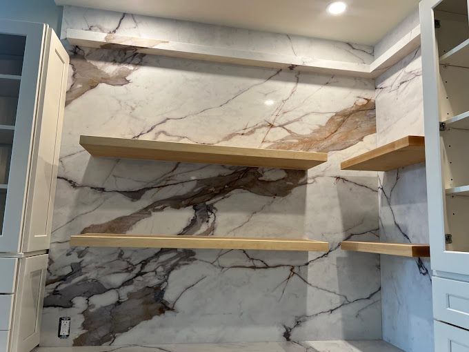 A kitchen with marble walls and wooden shelves