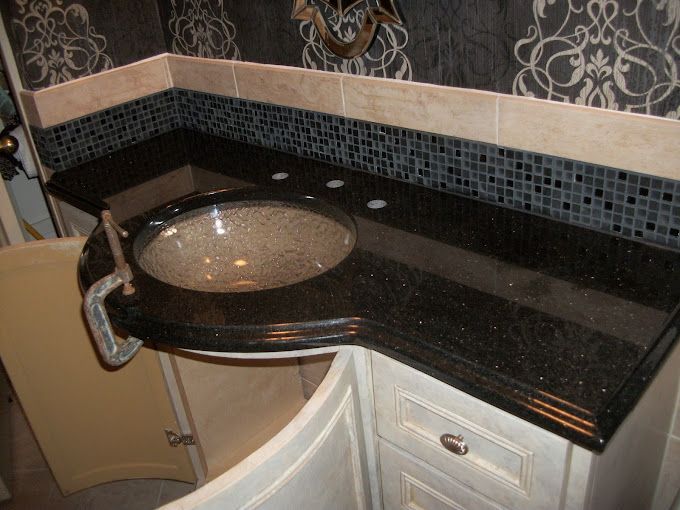 A bathroom with a black counter top and a sink