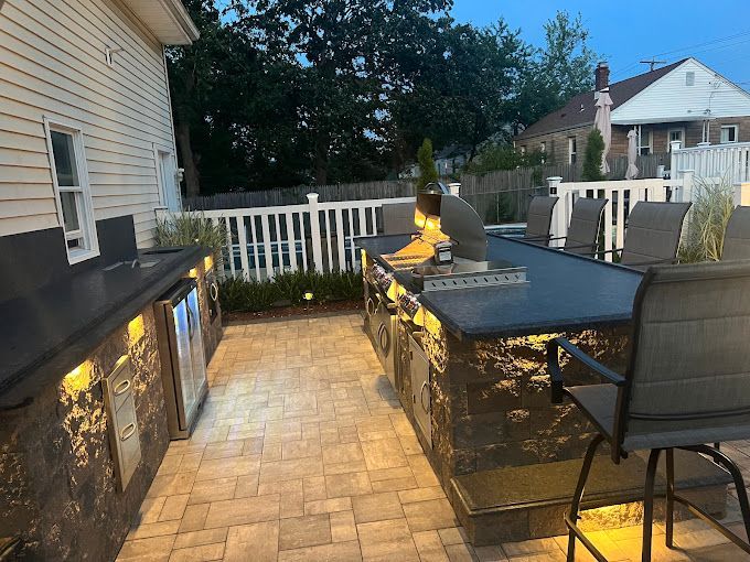 A large outdoor kitchen with a grill and a table and chairs.