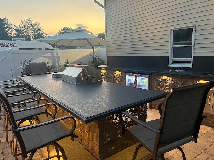 A long table with chairs and an umbrella in front of a house.