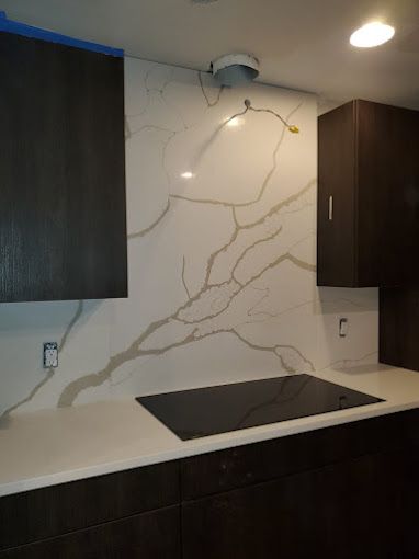 A kitchen with a stove top oven and a marble counter top.