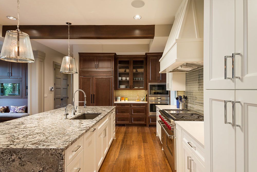 A kitchen with granite counter tops , wooden cabinets , stainless steel appliances and a large island.