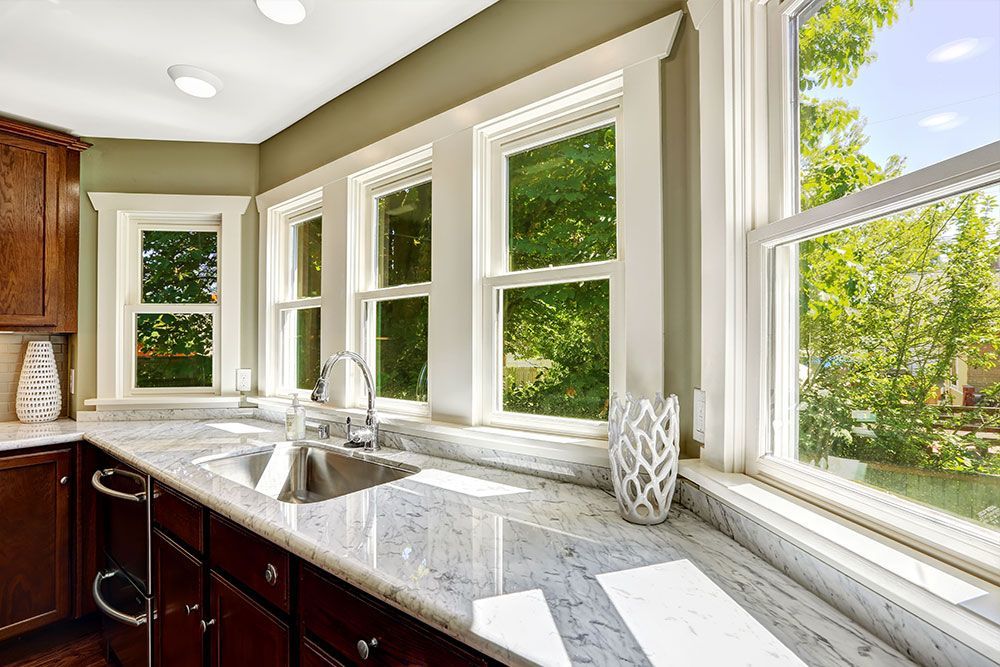 A kitchen with a sink , granite counter tops , and lots of windows.