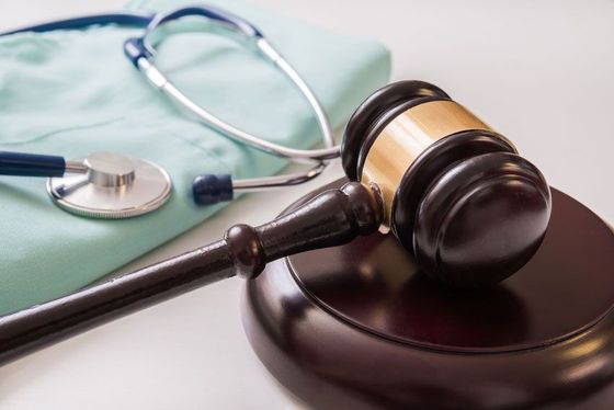 Gavel, stethoscope, and medical scrubs, representing medical law or healthcare litigation.