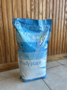 A bag of shady place is sitting on a tiled floor in front of a wooden wall.