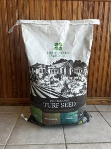 A bag of turf seed is sitting on a tiled floor.