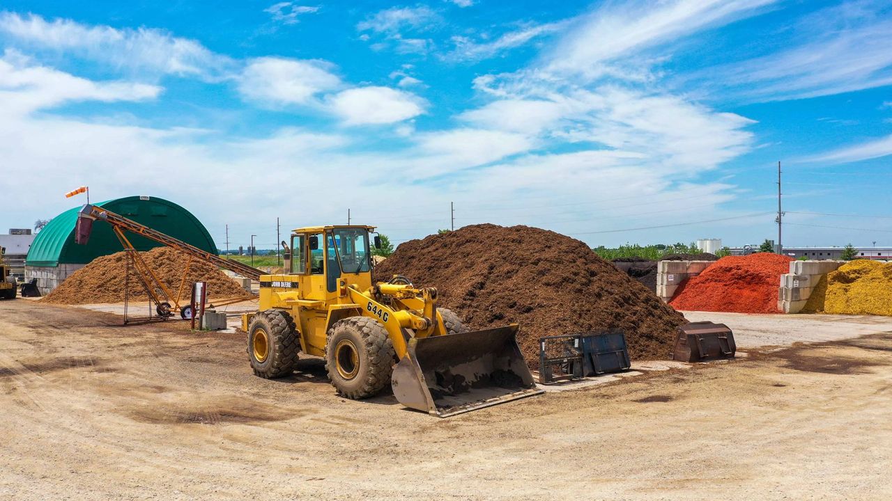 A yellow bulldozer is sitting in front of a pile of dirt.