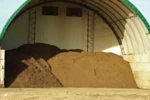 A large pile of dirt is sitting under a green roof.