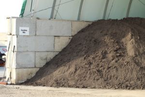 A large pile of dirt is sitting next to a brick wall.