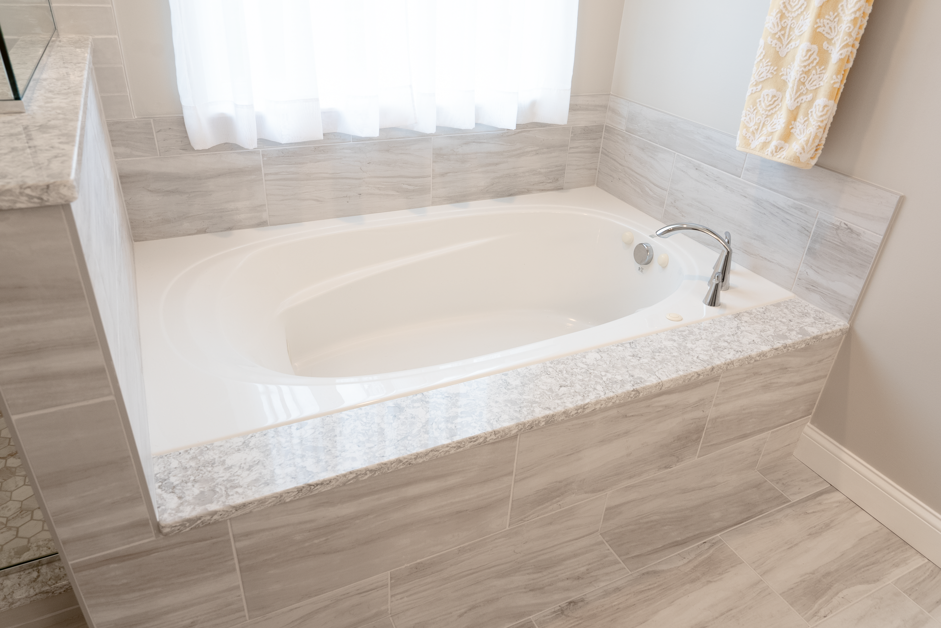 White bathtub with tiled surround in a modern bathroom.