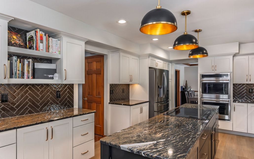A kitchen with white cabinets, granite counter tops, stainless steel appliances and a large island.