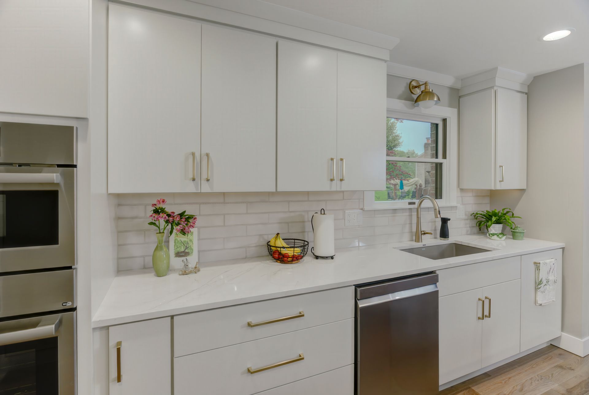 A kitchen with white cabinets, stainless steel appliances, a sink, and a window.