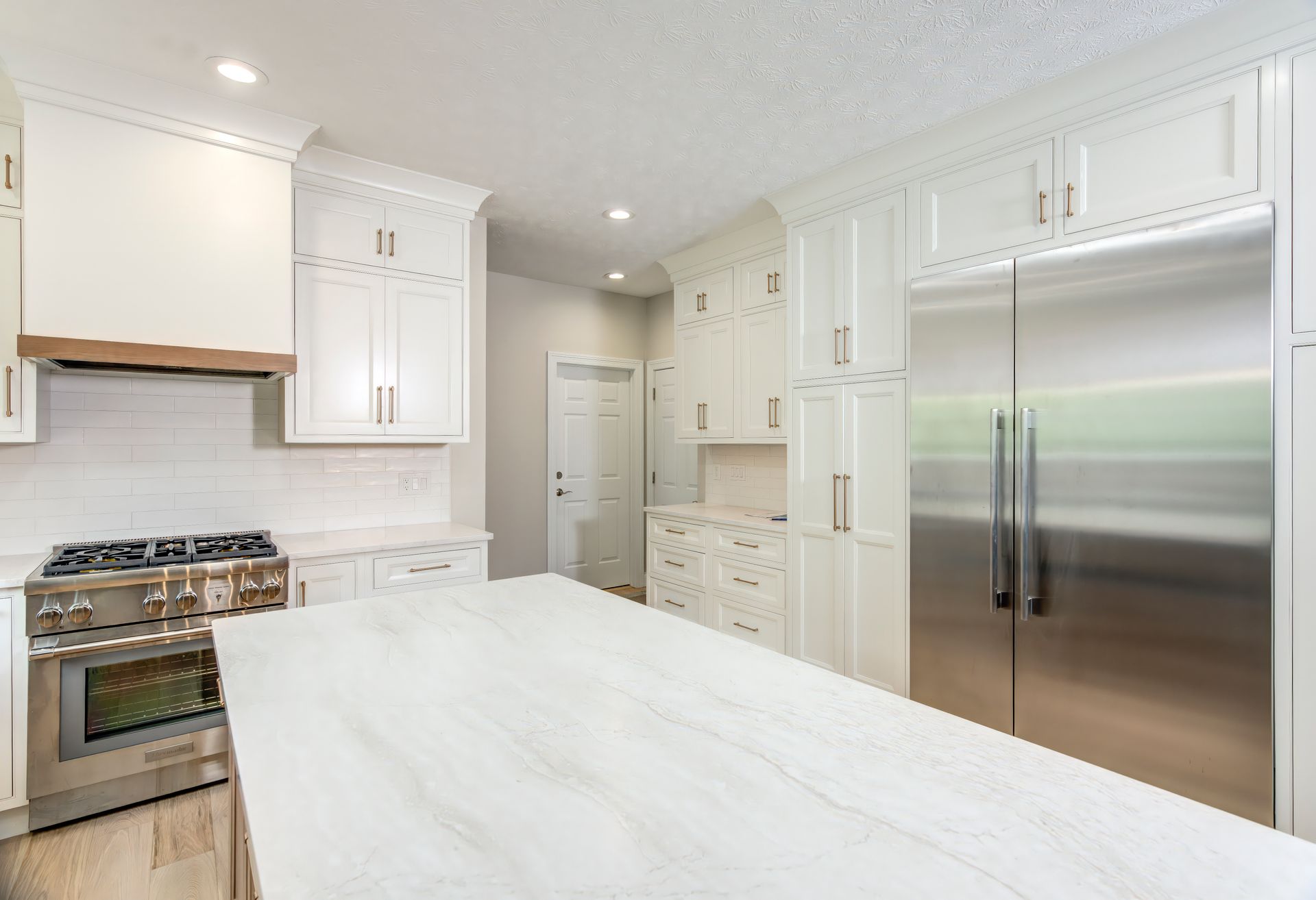 A kitchen with white cabinets, stainless steel appliances, and a large island.