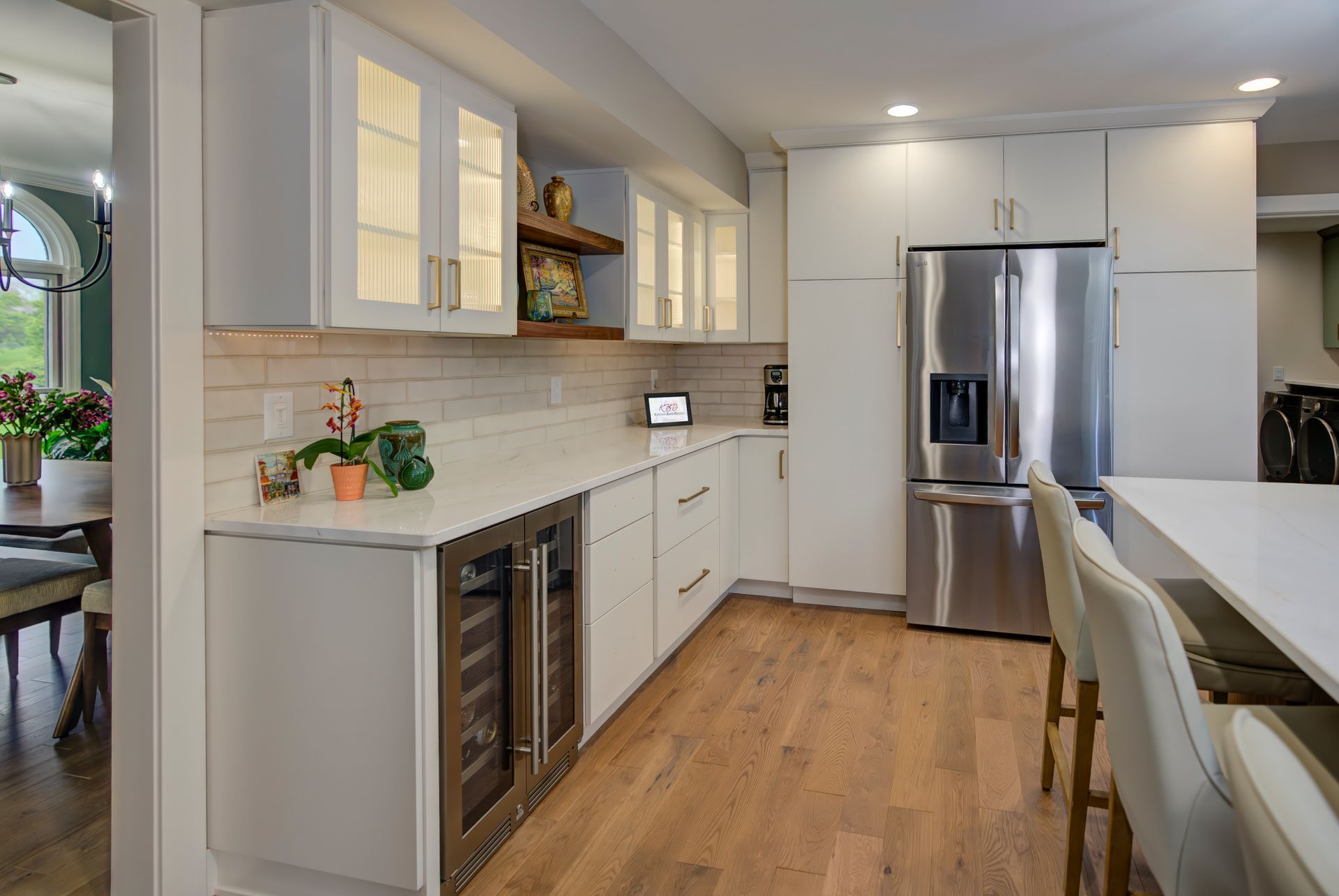 A kitchen with white cabinets, stainless steel appliances, a refrigerator and a wine cooler.