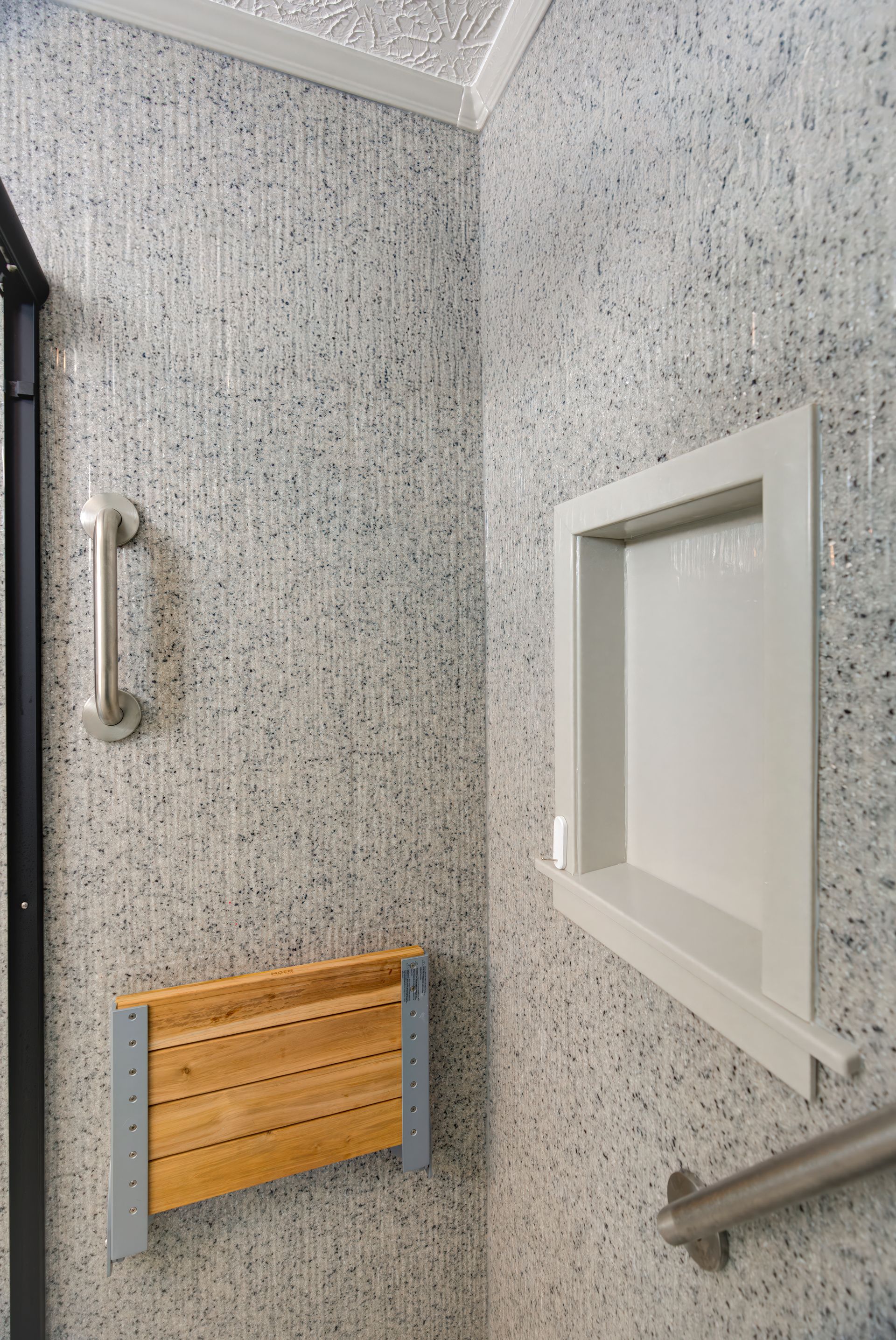 A bathroom with a shower seat and a window.