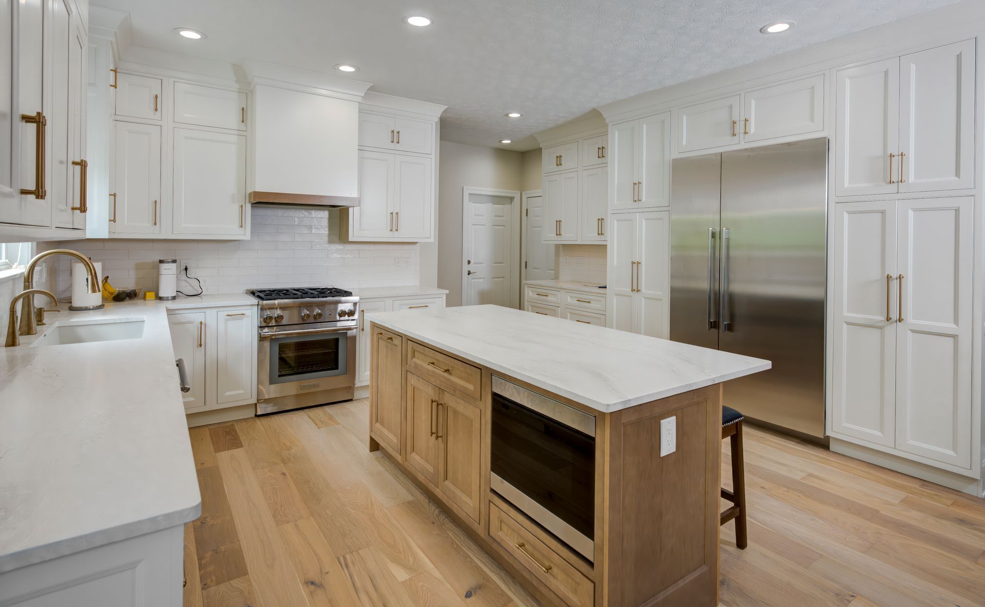 A kitchen with white cabinets, stainless steel appliances, and a large island.