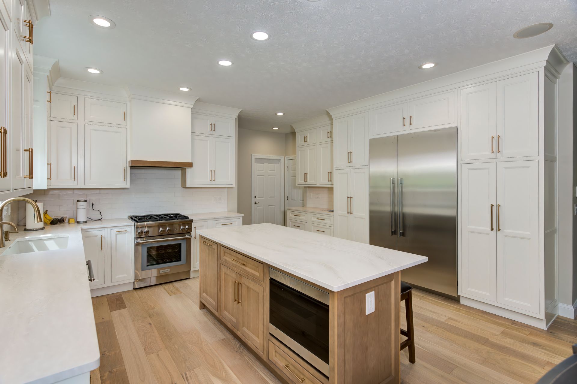 A kitchen with white cabinets, stainless steel appliances, and a large island.