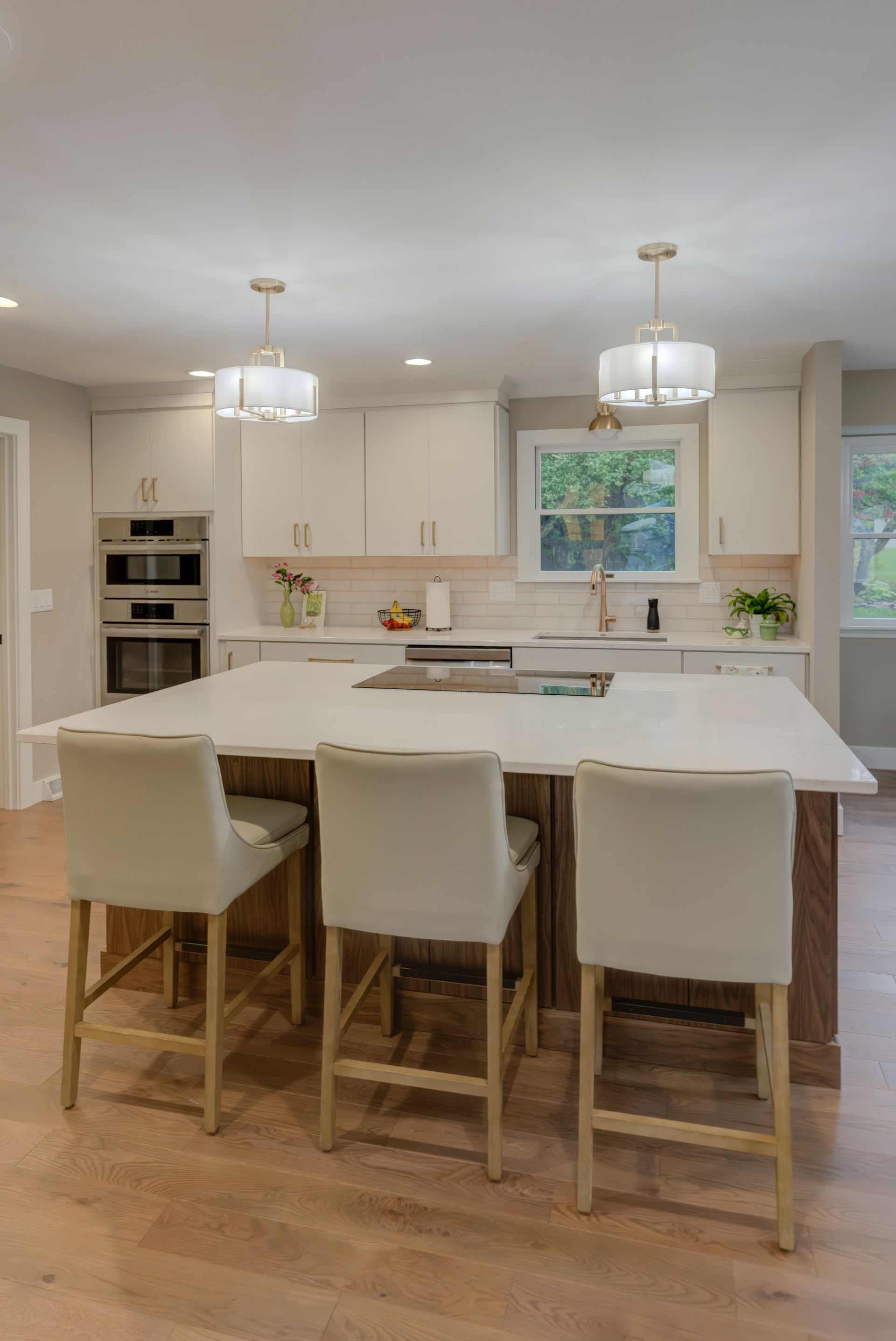 A kitchen with a large island and chairs in it.