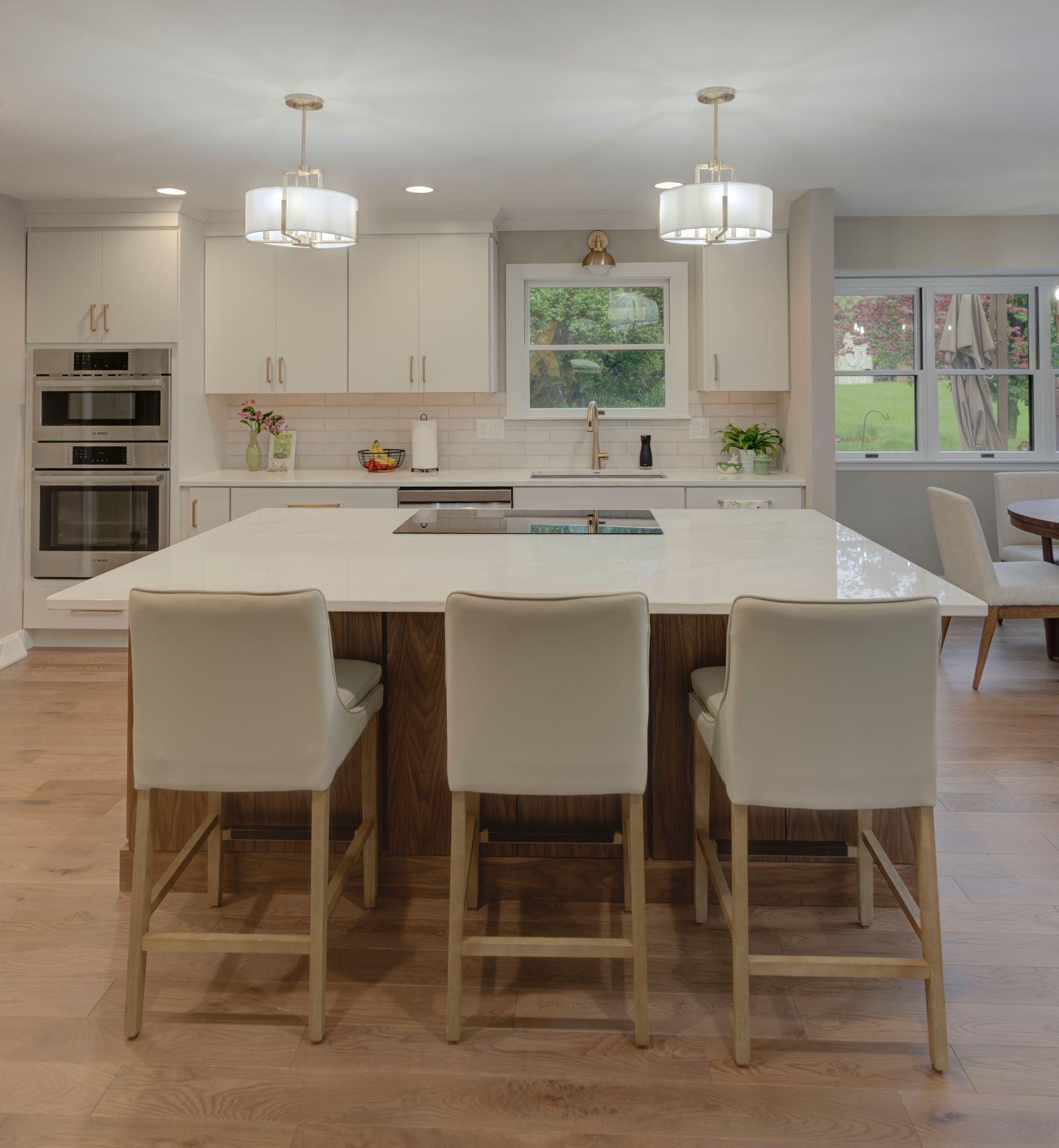 A kitchen with a large island and white chairs